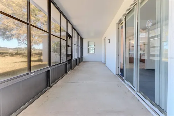 a view of an empty room with a window and a kitchen
