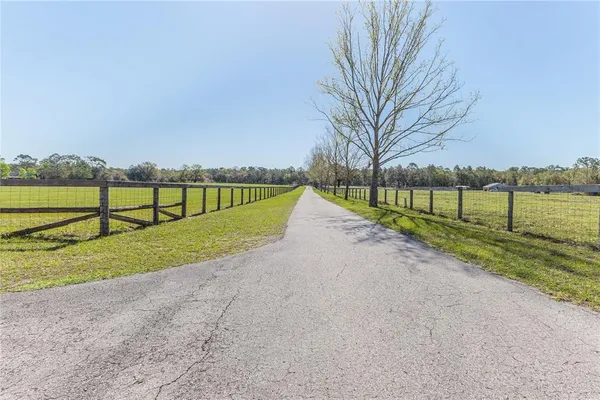 an empty room with chandelier fan and windows