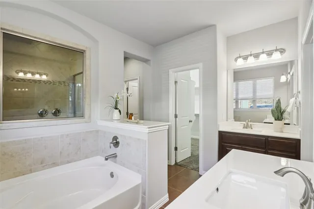 a spacious bathroom with a tub sink and mirror