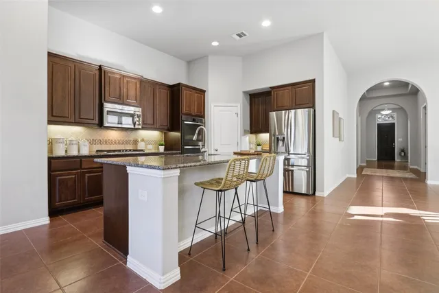 a kitchen with stainless steel appliances granite countertop a refrigerator and a stove top oven