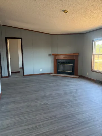 an empty room with wooden floor fireplace and windows