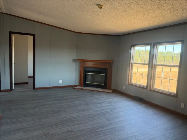 an empty room with wooden floor and fireplace