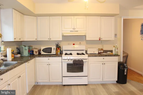 a kitchen with granite countertop white cabinets and white appliances