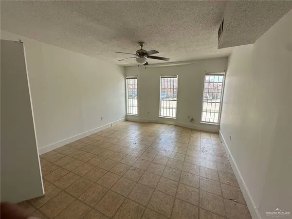 a view of an empty room with window and chandelier fan
