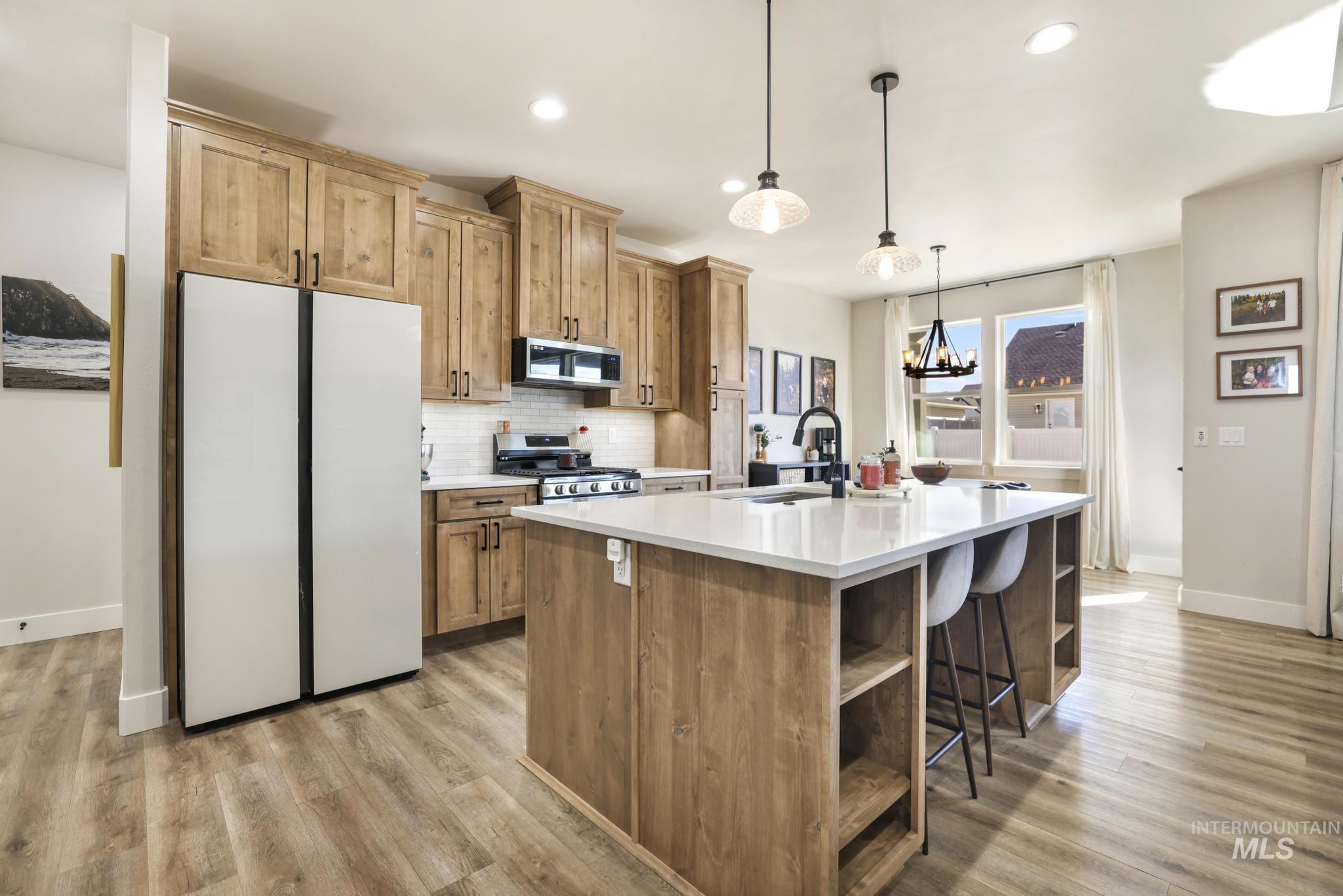 1231 Frank Henry Road Twin Falls, ID 83301 - Photo 11 of 48 Kitchen with stainless steel appliances, open shelves, a kitchen island with sink, light wood-style floors, and a breakfast bar area