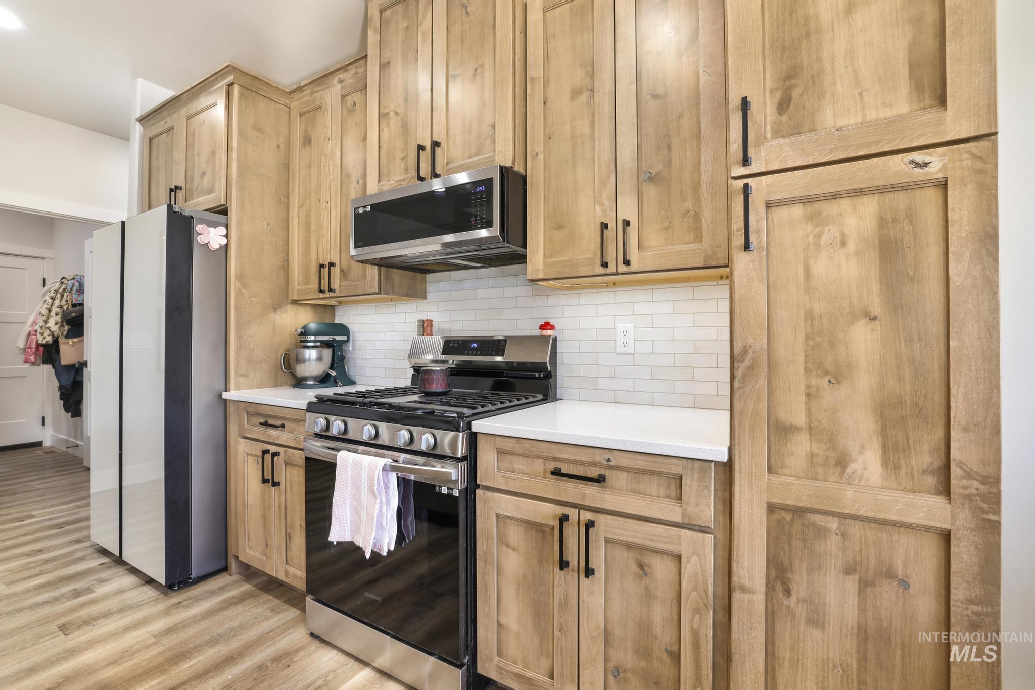 1231 Frank Henry Road Twin Falls, ID 83301 - Photo 12 of 48 Kitchen featuring stainless steel appliances, tasteful backsplash, light wood-style flooring, light stone counters, and light wood finish cabinetry