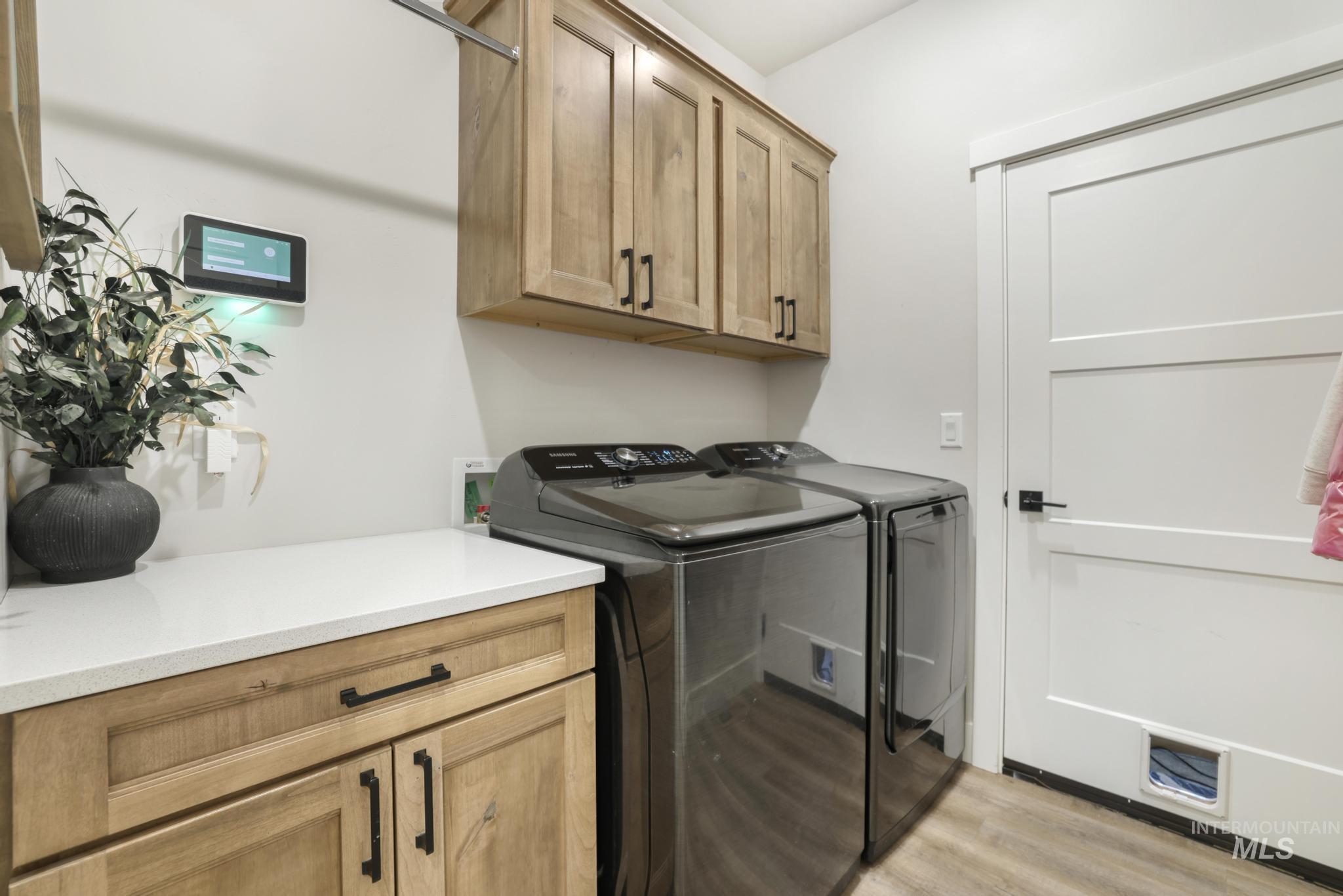 1231 Frank Henry Road Twin Falls, ID 83301 - Photo 16 of 48 Laundry room with cabinet space, light wood-style flooring, and washer and clothes dryer