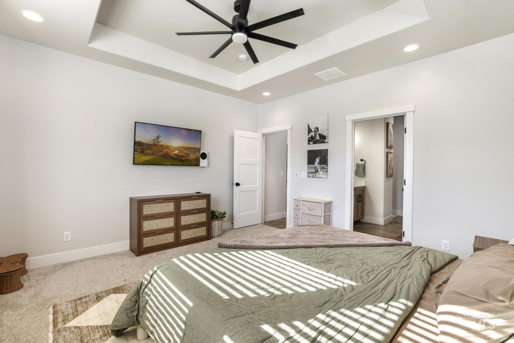 1231 Frank Henry Road Twin Falls, ID 83301 - Photo 18 of 48 Bedroom with a tray ceiling, recessed lighting, a ceiling fan, connected bathroom, and carpet floors
