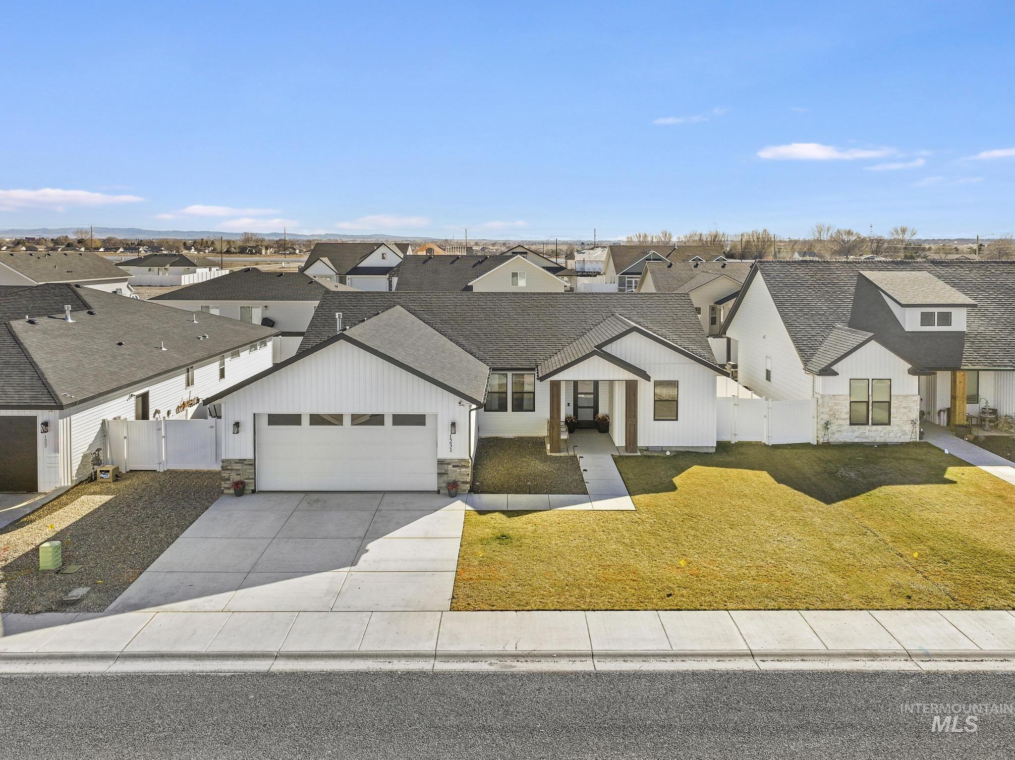 1231 Frank Henry Road Twin Falls, ID 83301 - Photo 2 of 48 Modern farmhouse featuring stone siding, a gate, a shingled roof, a residential view, and concrete driveway
