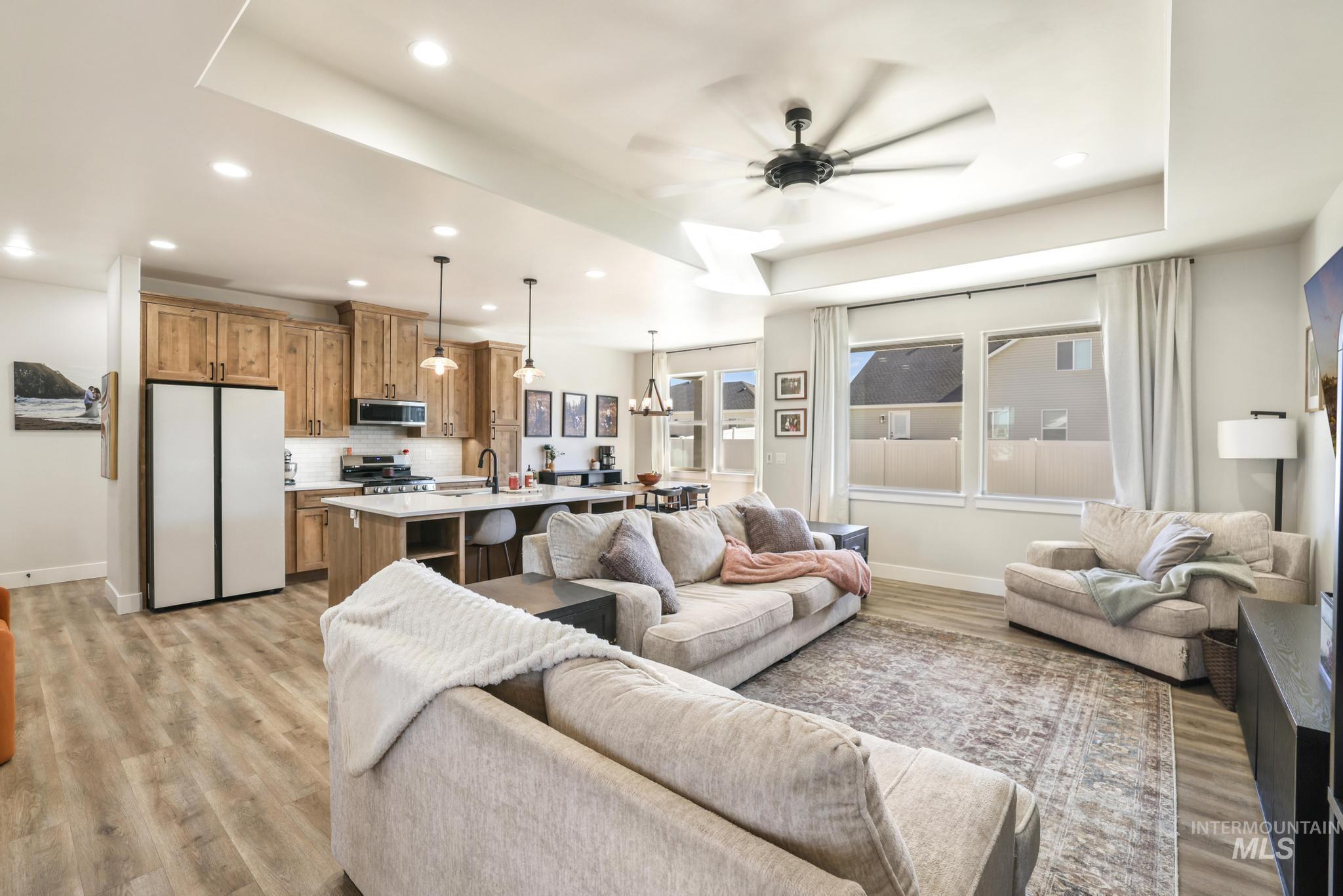 1231 Frank Henry Road Twin Falls, ID 83301 - Photo 9 of 48 Living area featuring ceiling fan, light wood-style flooring, a tray ceiling, and suspended lighting