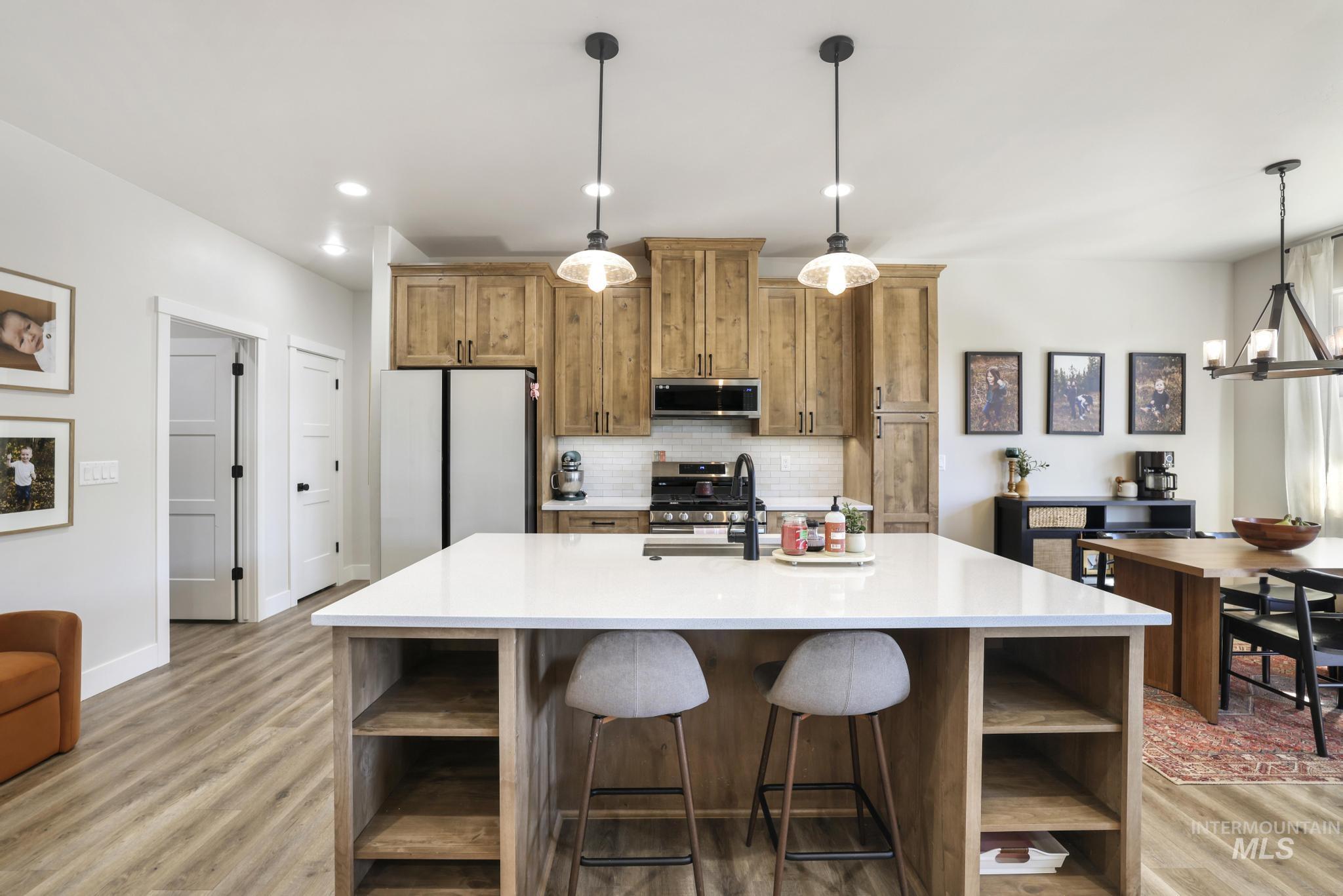 1231 Frank Henry Road Twin Falls, ID 83301 - Photo 10 of 48 Kitchen with open shelves, wood finish cabinetry, stainless steel appliances, a kitchen island with sink, and light stone counters