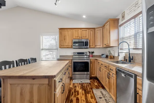 a kitchen with stainless steel appliances granite countertop a sink a stove a refrigerator cabinets and a window