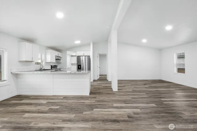 a kitchen with stainless steel appliances granite countertop a refrigerator sink and white cabinets