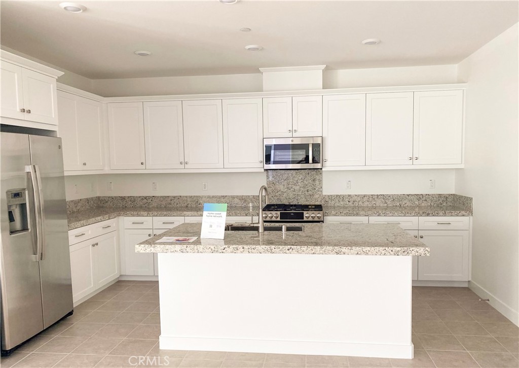 a kitchen with kitchen island granite countertop a stove top oven a sink a counter space and cabinets