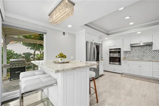 a kitchen with stainless steel appliances granite countertop a stove a refrigerator a oven with white cabinets and wooden floor