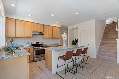 a kitchen with stainless steel appliances kitchen island granite countertop a stove a sink and a refrigerator