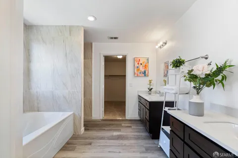 a spacious bathroom with a double vanity sink a large mirror and a bathtub