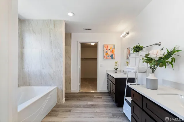 a spacious bathroom with a double vanity sink a large mirror and a bathtub