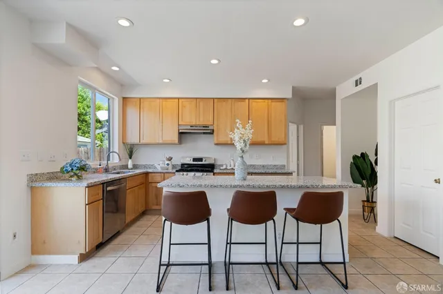 a kitchen with stainless steel appliances granite countertop wooden cabinets a stove top oven a sink a dining table and chairs