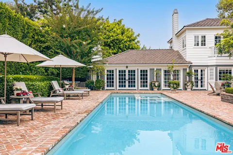 a view of patio with chairs and table under an umbrella with a barbeque grill and couches