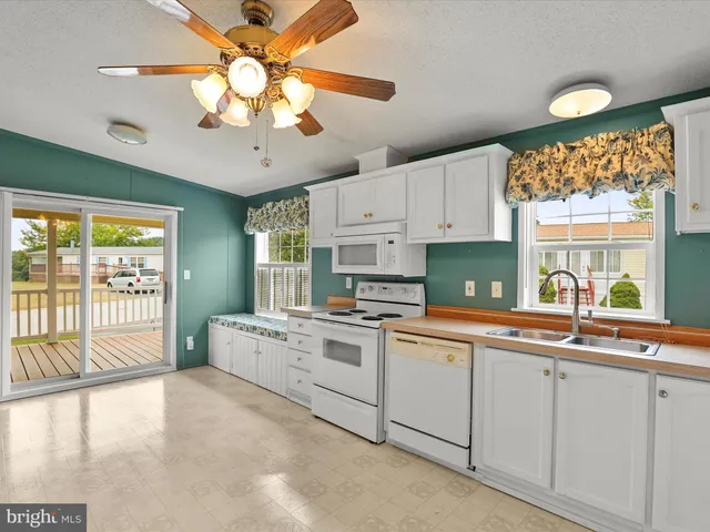a kitchen with a stove a sink and white cabinets with wooden floor
