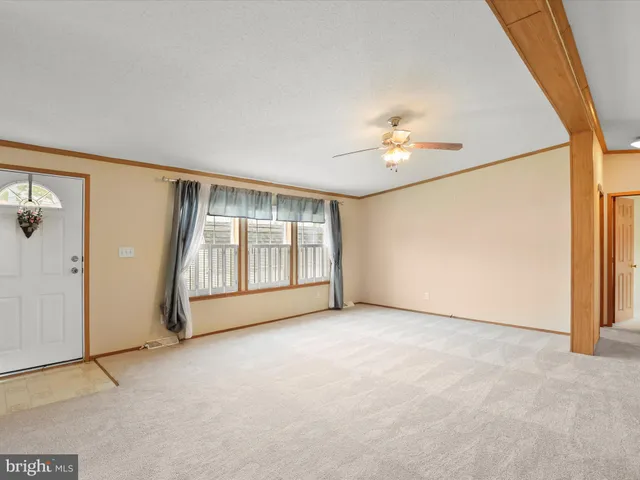 an empty room with chandelier fan and windows