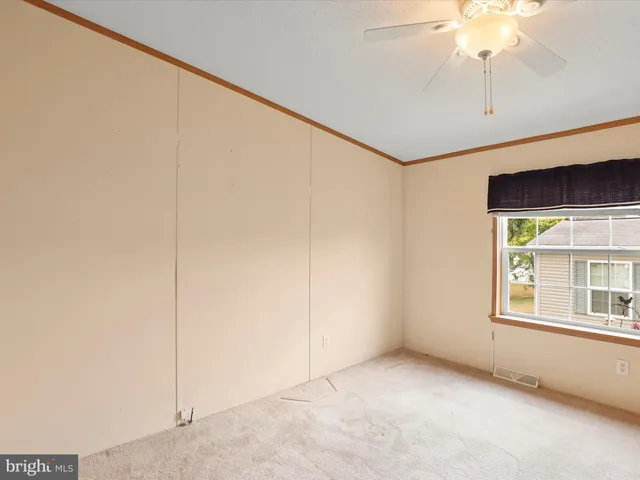 an empty room with a chandelier fan and windows