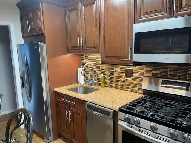 a kitchen with granite countertop a sink stainless steel appliances and cabinets