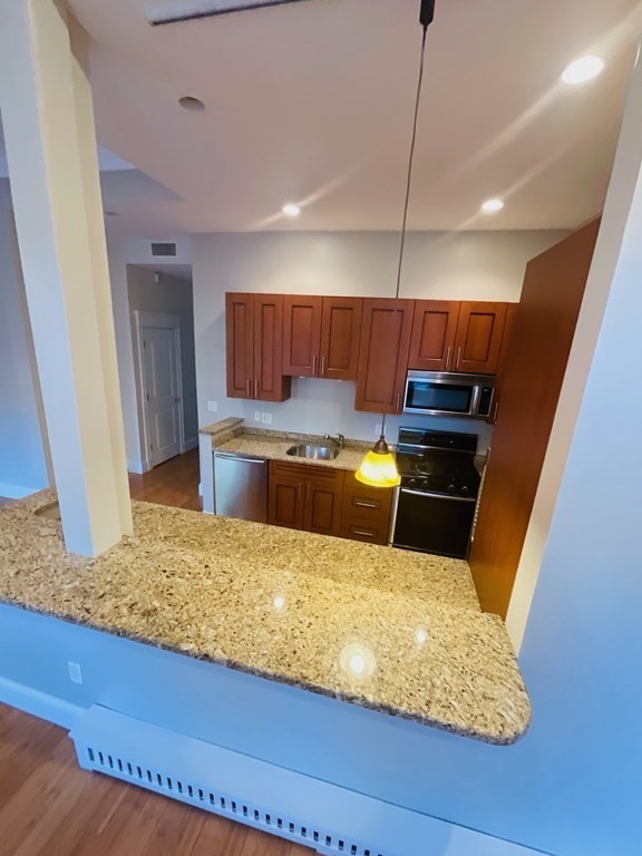 13 Worcester Square, Unit 2 Boston, MA 02118 - Photo 4 of 16 a kitchen with kitchen island granite countertop wooden cabinets a sink and a stove
