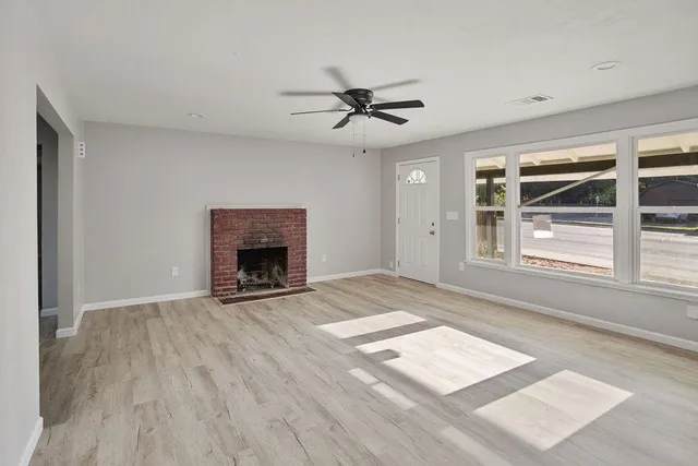 a view of an empty room with a window and wooden floor