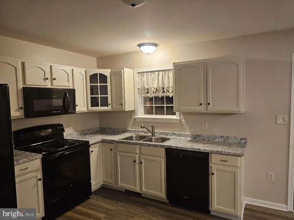 a kitchen with stainless steel appliances granite countertop a sink dishwasher stove and microwave with wooden cabinets