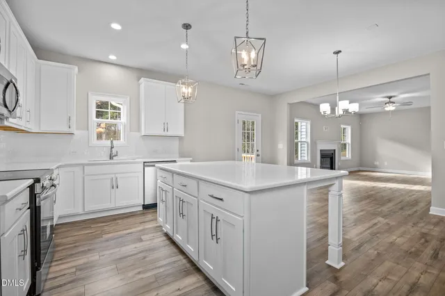 a kitchen with kitchen island granite countertop a sink cabinets and wooden floor