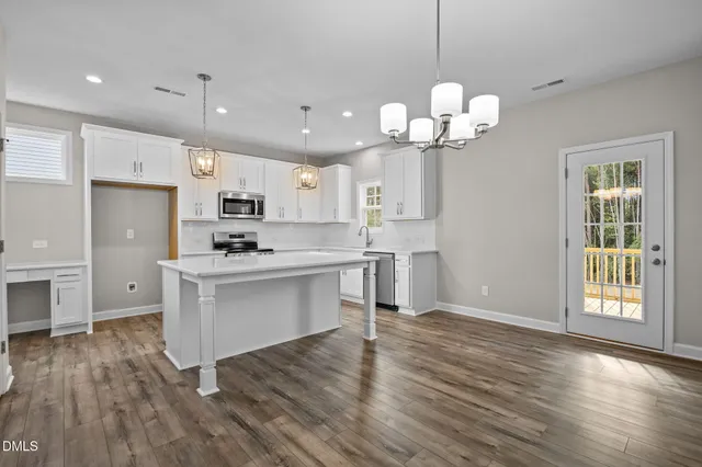 a kitchen with stainless steel appliances granite countertop a refrigerator a sink dishwasher a stove and white cabinets with wooden floor