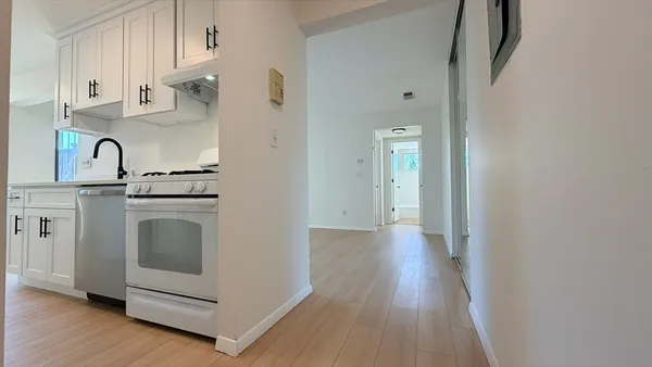 a kitchen with white cabinets and wooden floor