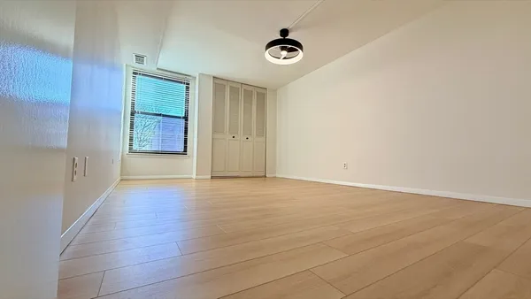 a view of an empty room with window and wooden floor