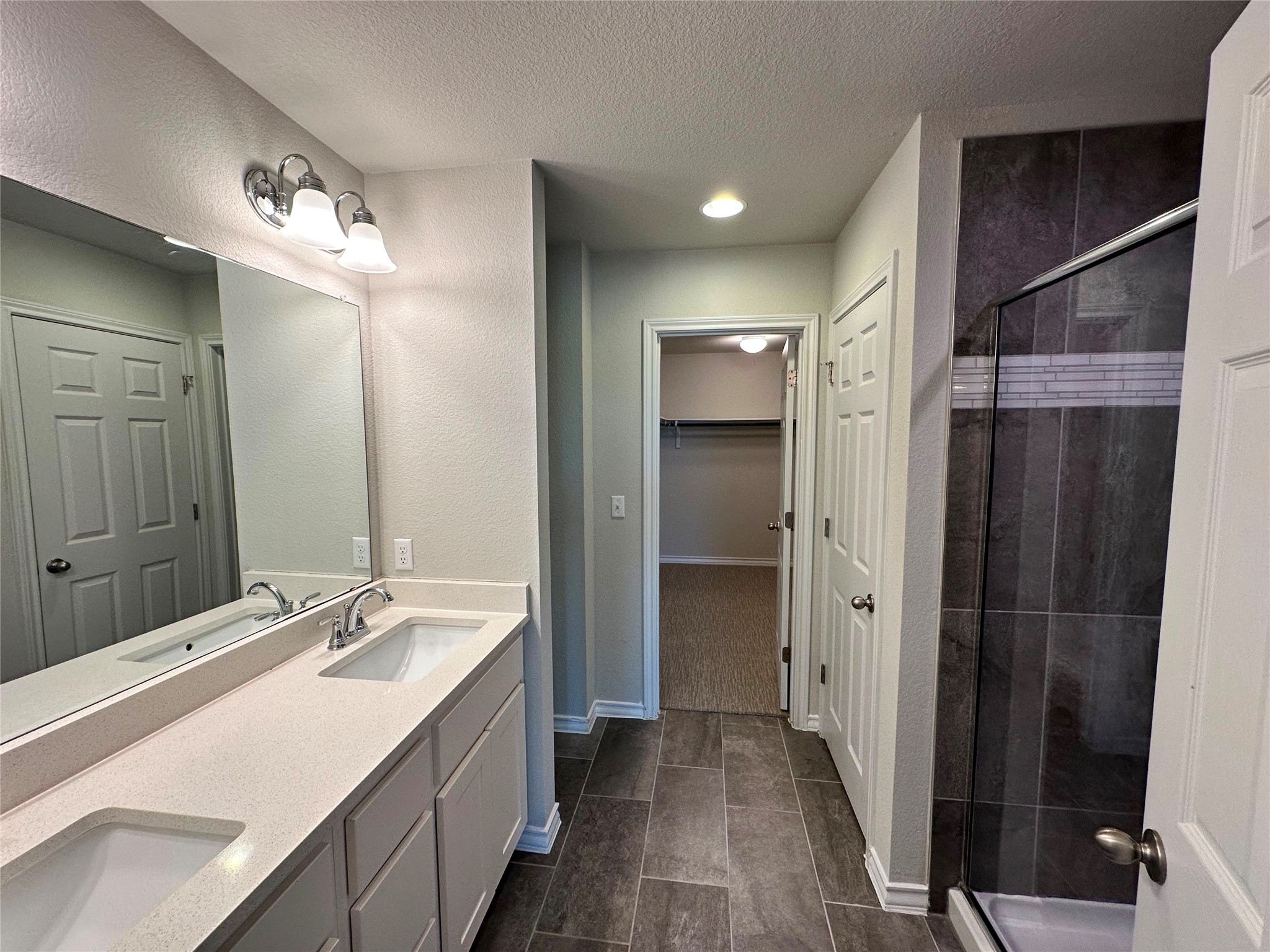 1624 Caballo Blanco Road Austin, TX 78725 - Photo 17 of 23 Double vanity and a tiled shower create a sleek and functional bathroom space.