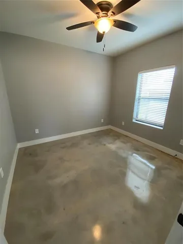 an empty room with a window and a fan