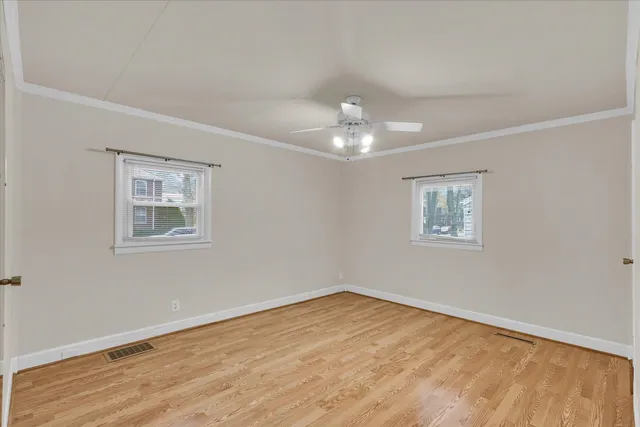a view of an empty room with a window and wooden floor