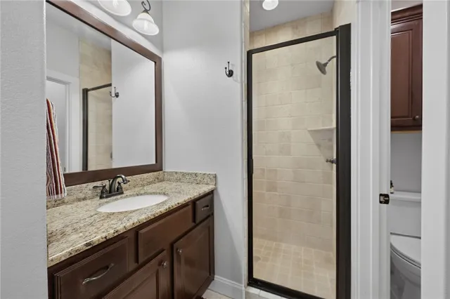 a bathroom with a granite countertop sink a toilet and a mirror