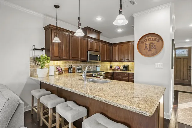 a kitchen with kitchen island granite countertop a sink a stove and a wooden cabinets