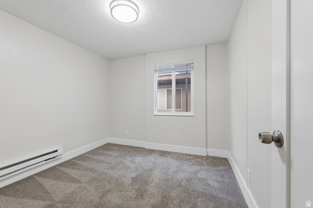 831 Lennox Street, Unit 5 Midvale, UT 84047 - Photo 13 of 19 Unfurnished room featuring light carpet, a baseboard heating unit, and a textured ceiling