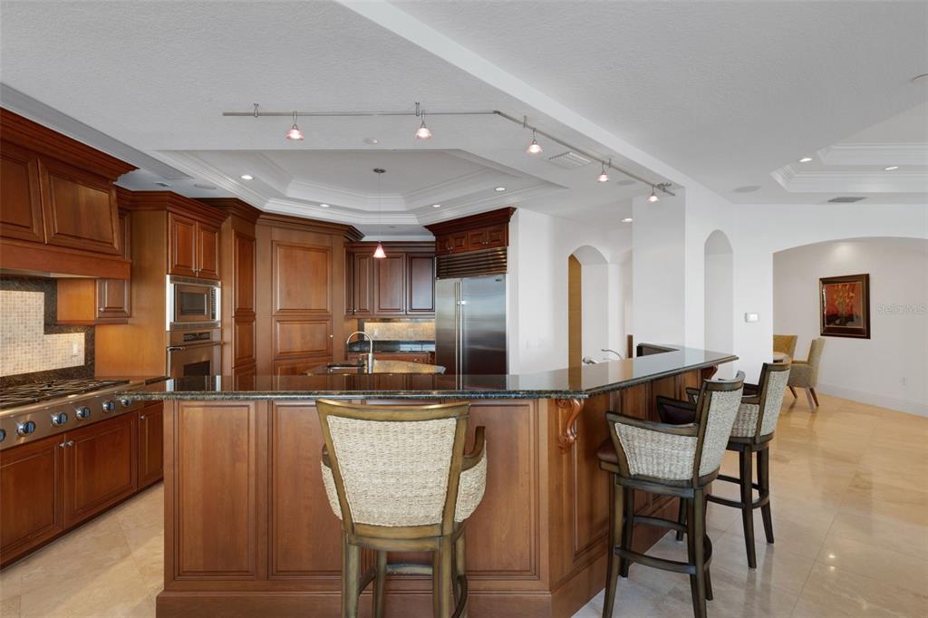 464 Golden Gate Point, Unit 403 Sarasota, FL 34236 - Photo 31 of 95 a kitchen with stainless steel appliances kitchen island granite countertop a stove a sink a refrigerator and chairs