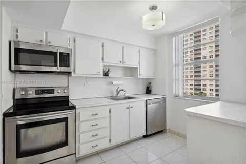 a kitchen with stainless steel appliances white cabinets a stove a sink and a microwave