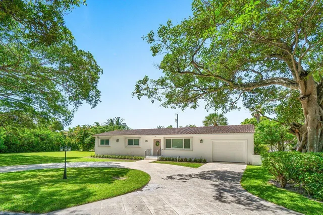a front view of a house with a yard and potted plants