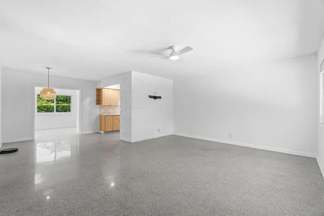 an empty room with a windows and chandelier fan