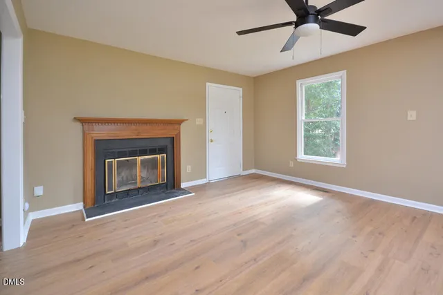 a view of empty room with a fireplace and wooden floor