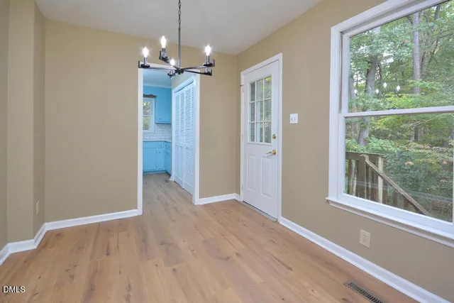 a view of a livingroom with a chandelier wooden floor and windows