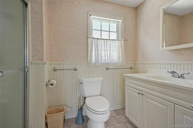 a bathroom with a granite countertop toilet a sink and a window