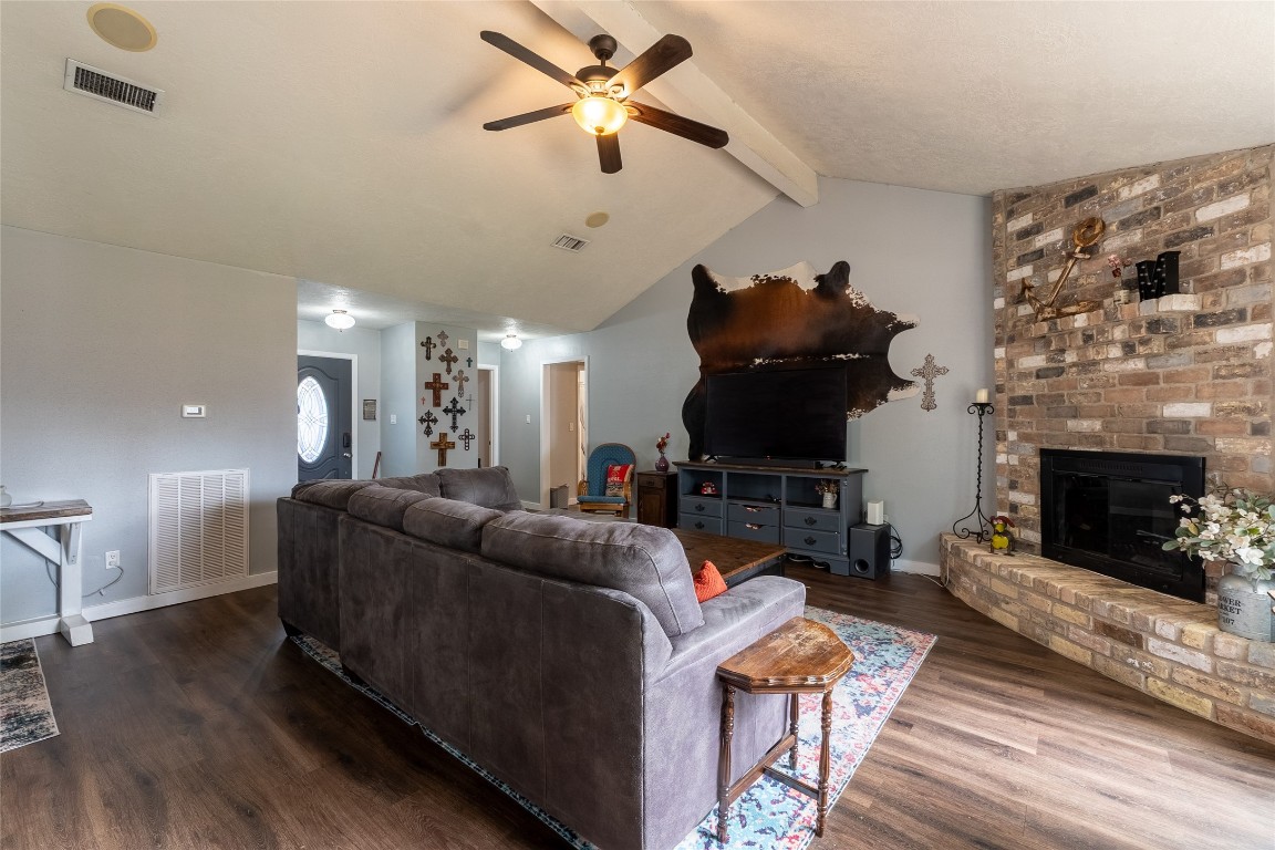 5818 Yorkgate Drive Spring, TX 77373 - Photo 4 of 19 Spacious living room featuring vaulted ceilings, a cozy brick fireplace, and wood-look flooring — perfect for relaxing or entertaining guests.