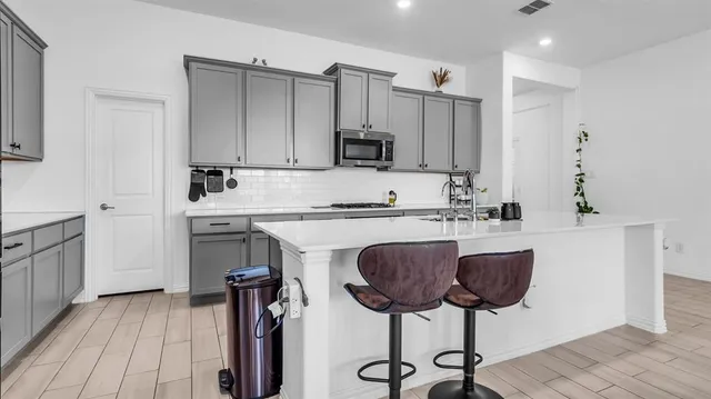 a kitchen with kitchen island granite countertop a sink cabinets and stainless steel appliances